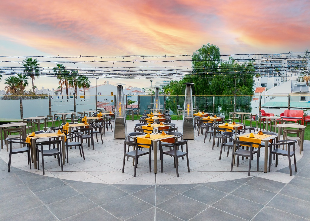 Terrasse du restaurant à Tenerife, ambiance extérieure avec tables et palmiers en arrière-plan.