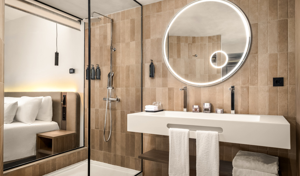 Salle de bain moderne avec miroir rond éclairé, douche et lavabo à Tenerife.