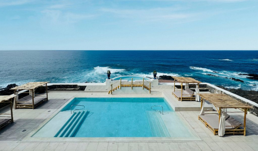 Piscine avec vue sur l'océan à Tenerife, entourée de chaises longues en bambou.