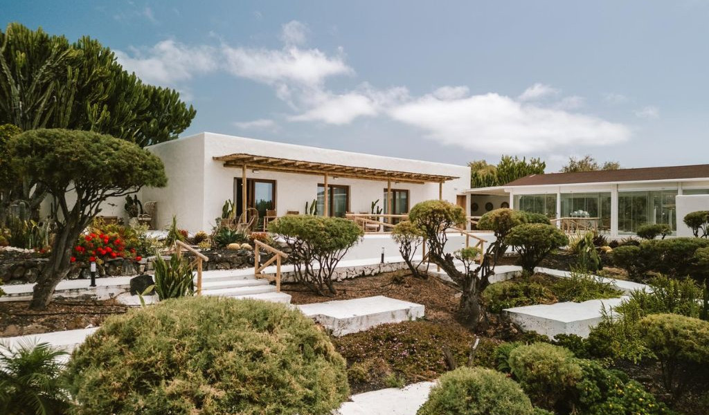 Bâtiment moderne et jardin à Tenerife avec ciel dégagé en arrière-plan.