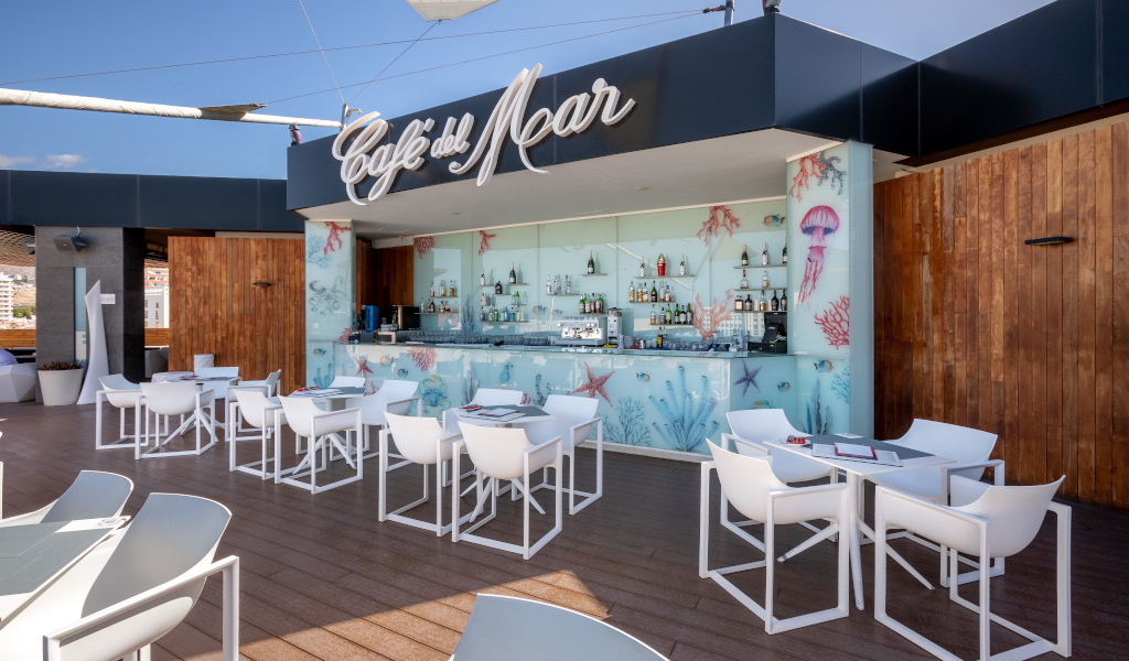 Terrasse du Café del Mar, Los Cristianos, avec tables et bar décoré d'éléments marins.