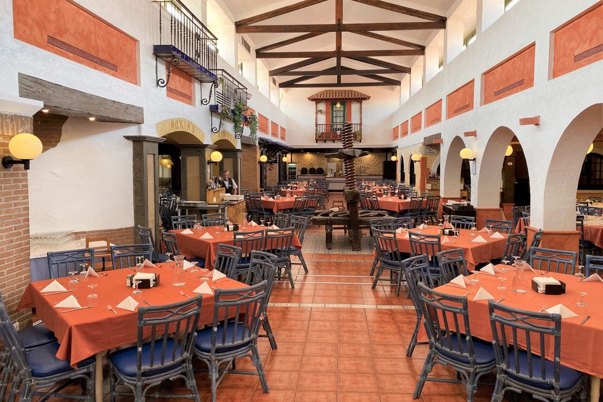 Salle de restaurant à Tenerife avec tables et chaises orange et bleues.