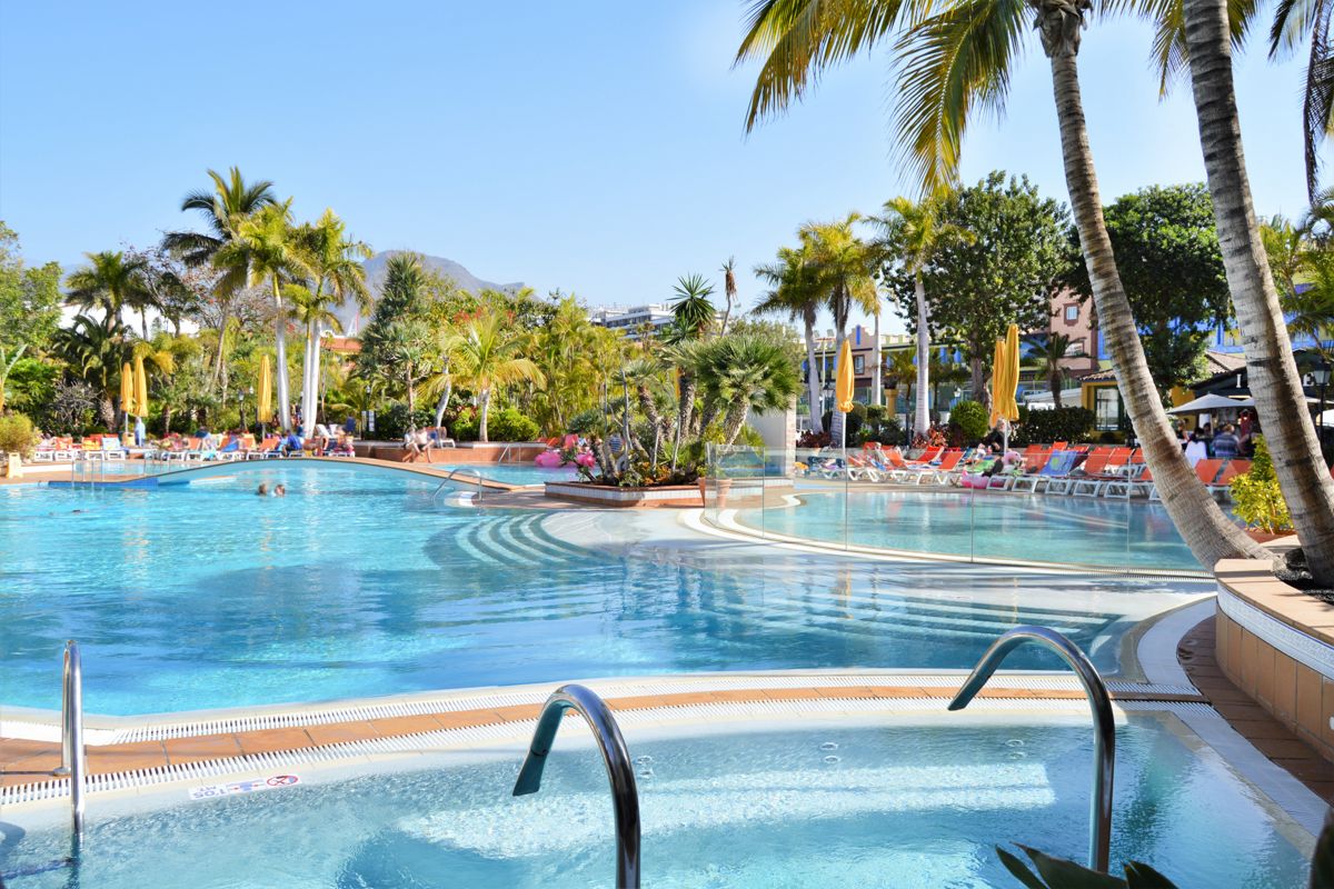 Piscine entourée de palmiers sous le ciel bleu à Tenerife.