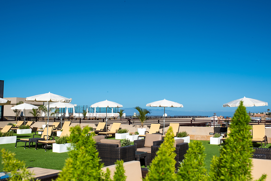 Transats et parasols sur le toit d'un hôtel à Tenerife avec ciel bleu.
