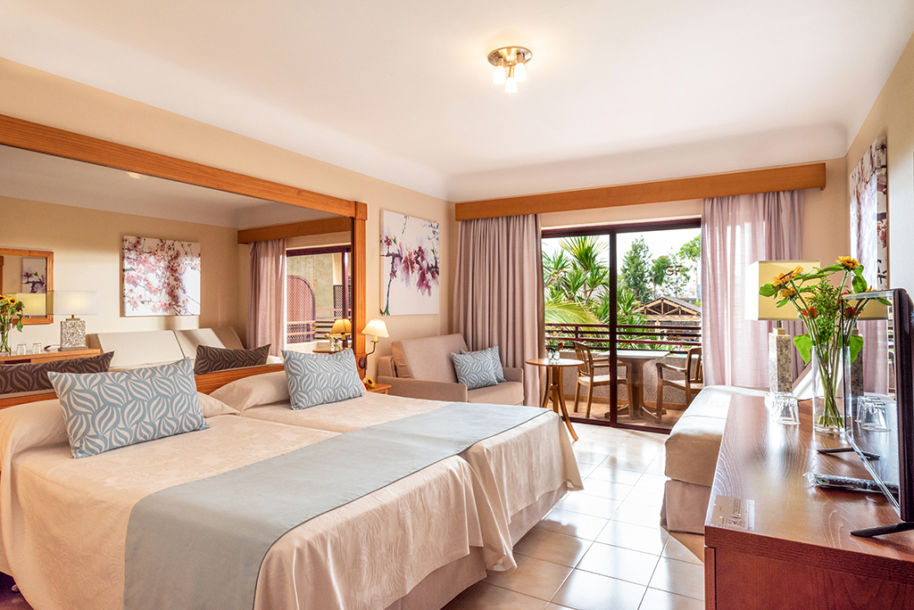 Chambre d'hôtel lumineuse à Tenerife avec lit double et balcon.