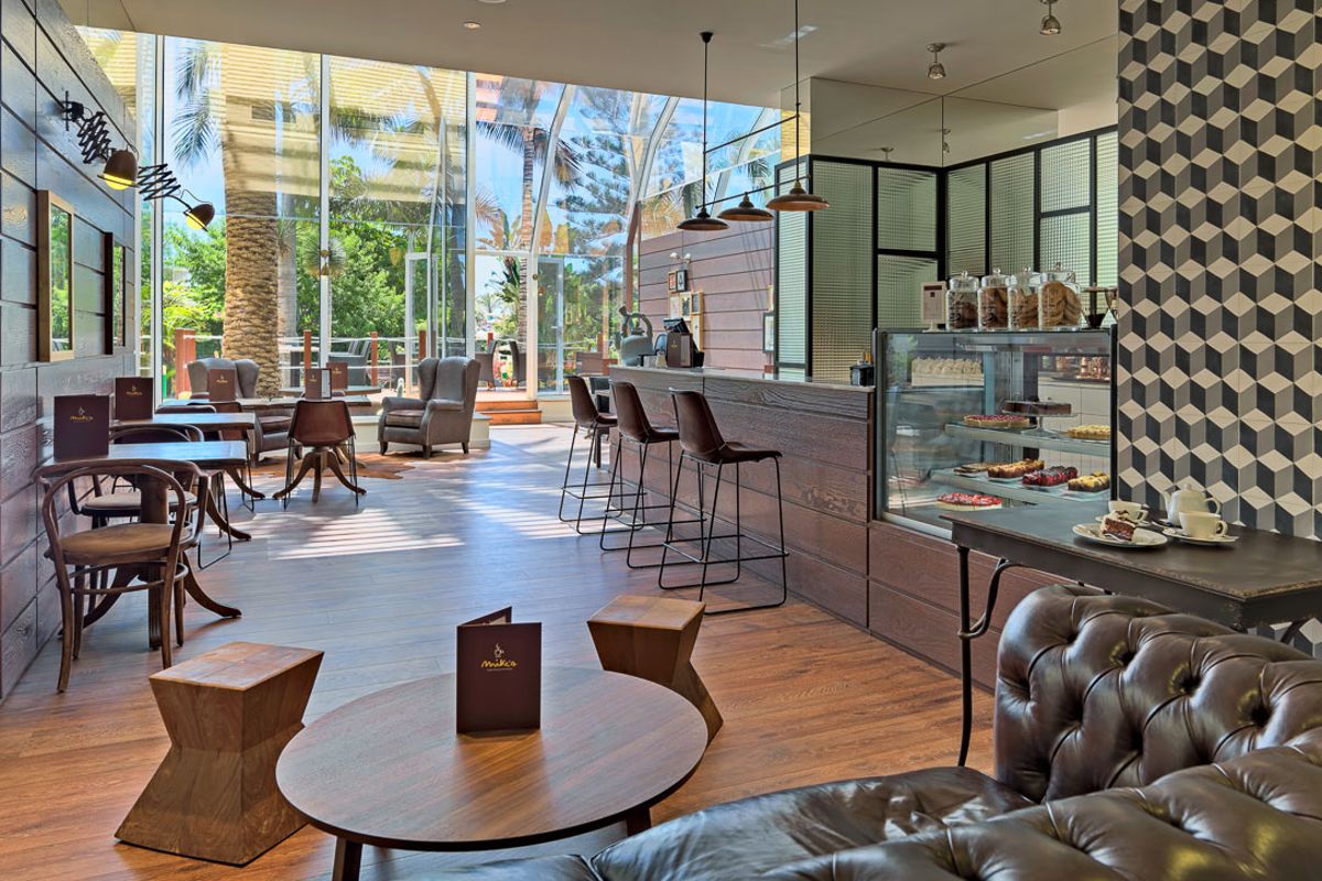 Café avec tables, fauteuils et présentoir à desserts, vue extérieure à Tenerife.