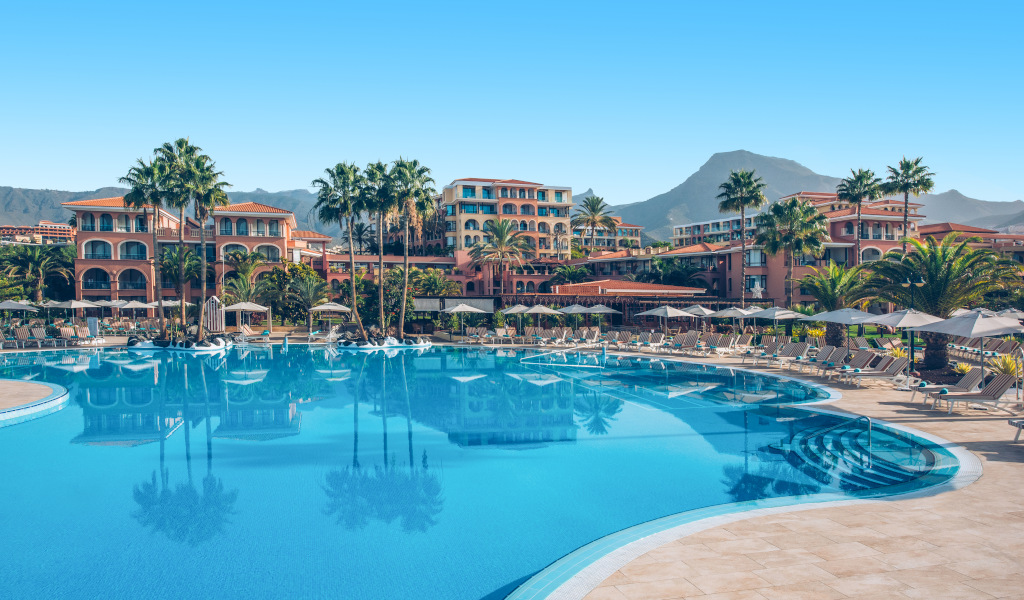 Piscine entourée de palmiers et bâtiments d'hôtel à Tenerife.