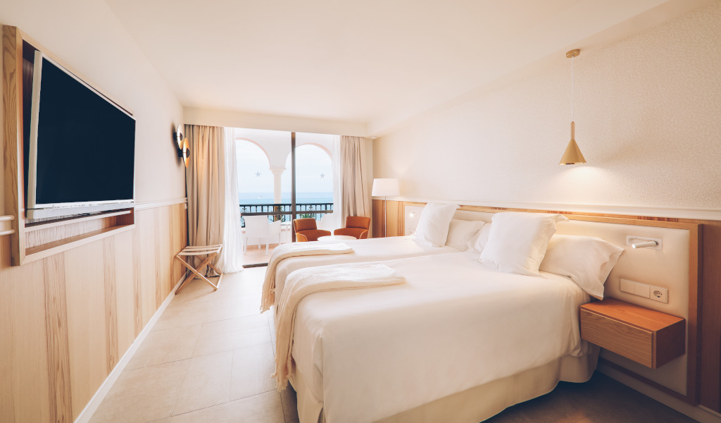 Chambre d'hôtel à Tenerife avec deux lits et vue sur le balcon.