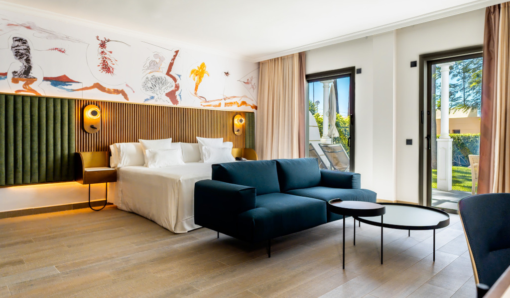 Chambre à Tenerife avec canapé bleu, lit double et vue sur jardin.