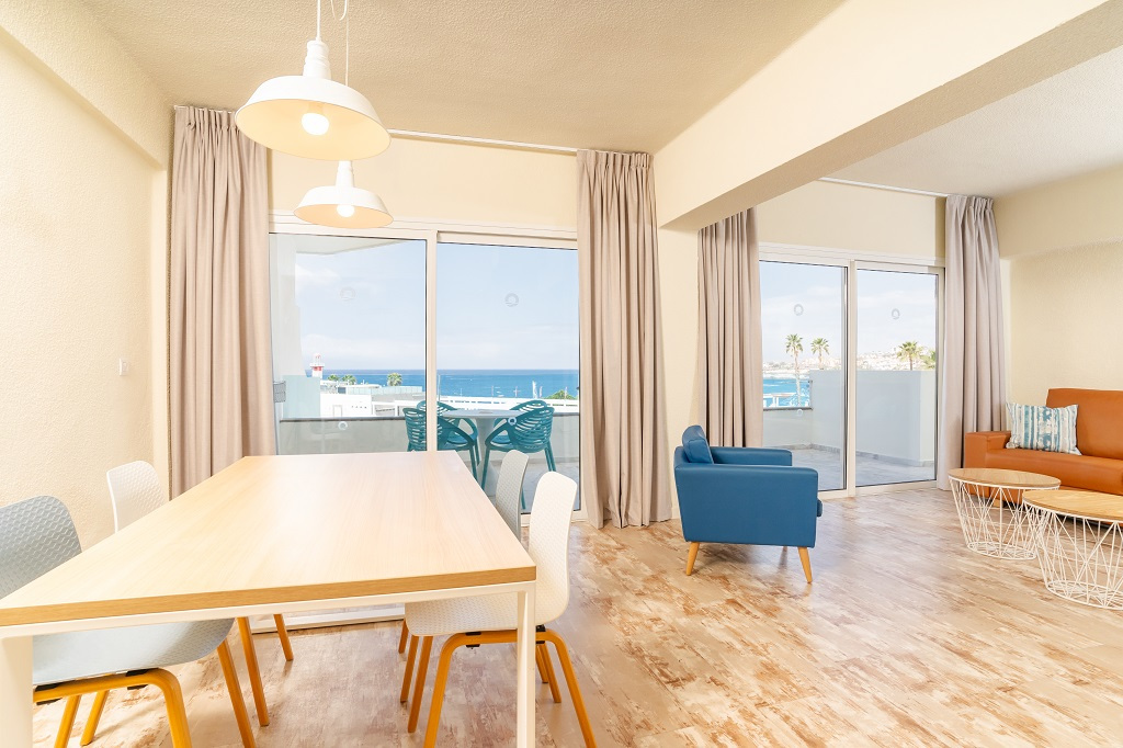Salon lumineux avec vue sur l'océan à Tenerife, table et canapé vers balcon.