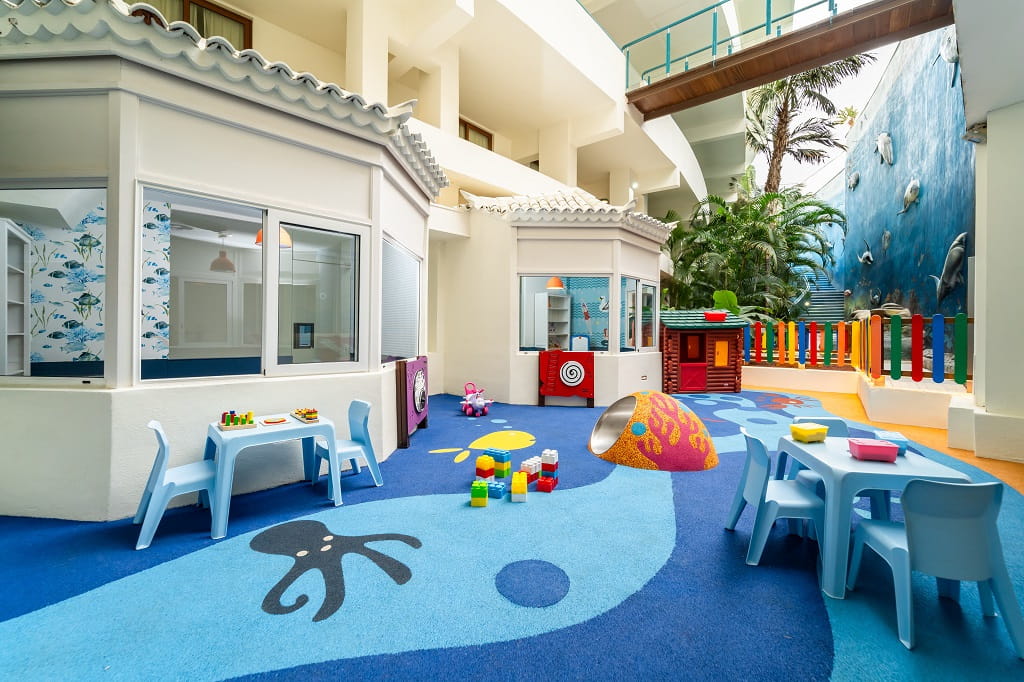 Espace de jeux intérieur pour enfants à Tenerife, avec tables, chaises et jouets colorés.