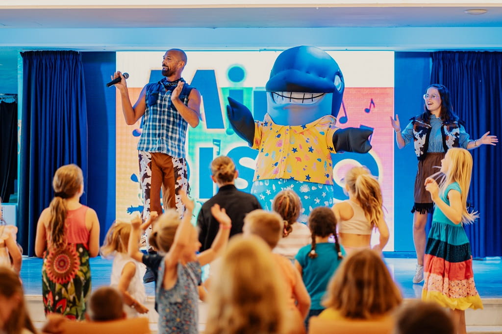 Un animateur et une mascotte de dauphin dansent avec des enfants à Tenerife.