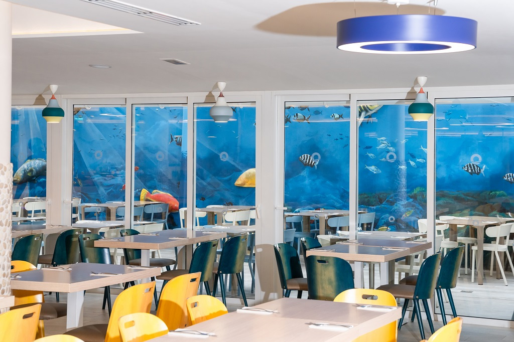 Salle à manger avec décoration sous-marine, poissons et tables alignées à Tenerife.