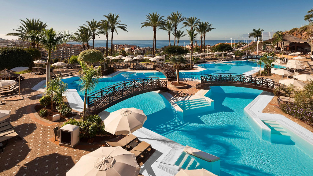 Piscines avec ponts et palmiers à Costa Adeje, Tenerife, avec vue sur l'océan.