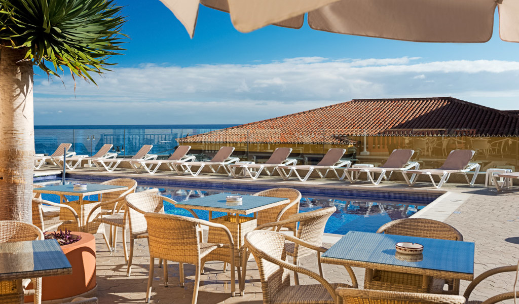 Transats et tables près de la piscine surplombant l'océan à Tenerife.