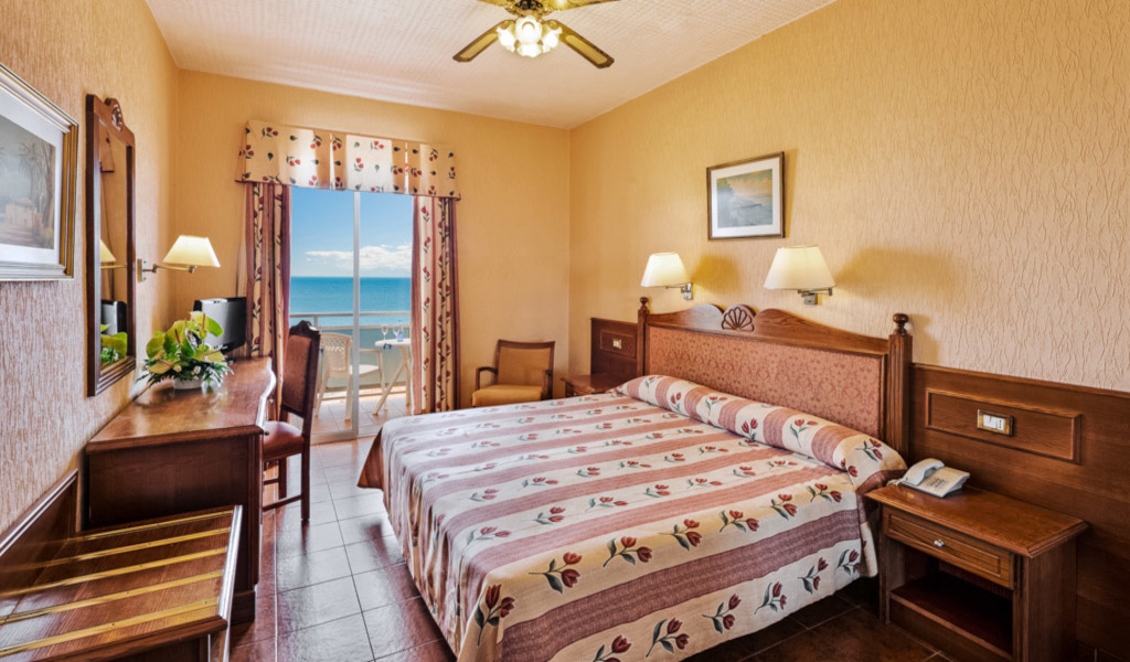 Chambre d'hôtel à Tenerife avec vue sur la mer à travers une porte-fenêtre.