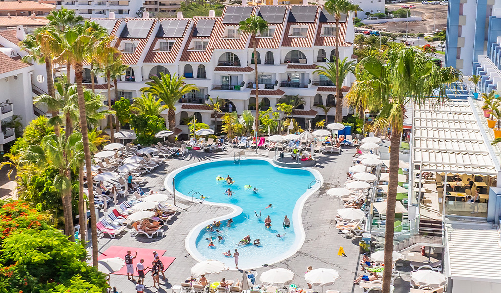 Piscine d'hôtel entourée de transats et palmiers à Tenerife.