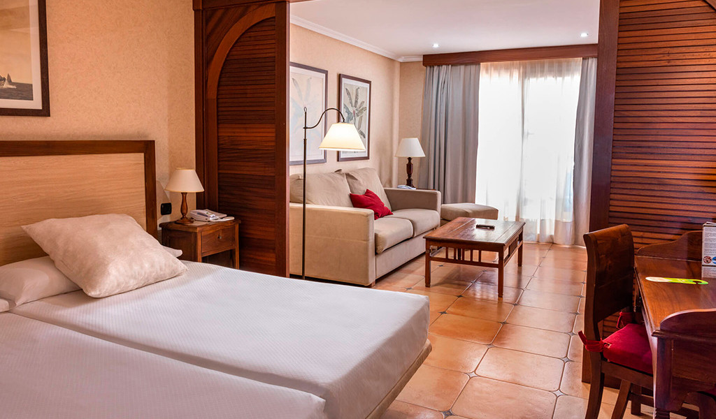 Chambre d'hôtel à Tenerife avec lits, canapé et table près d'une fenêtre.