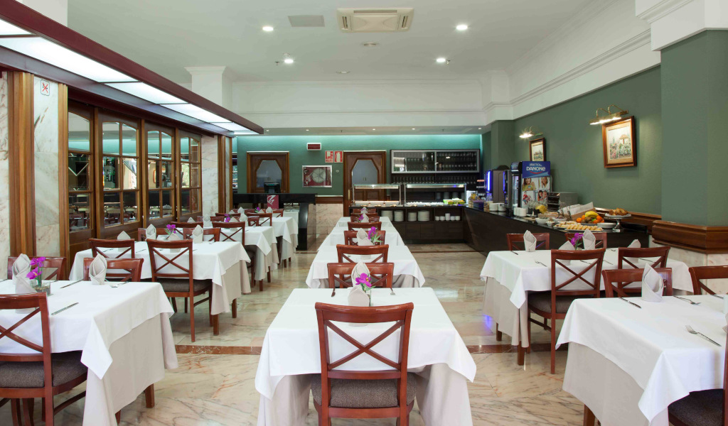 Salle de restaurant à Tenerife avec tables dressées et buffet à l’arrière.