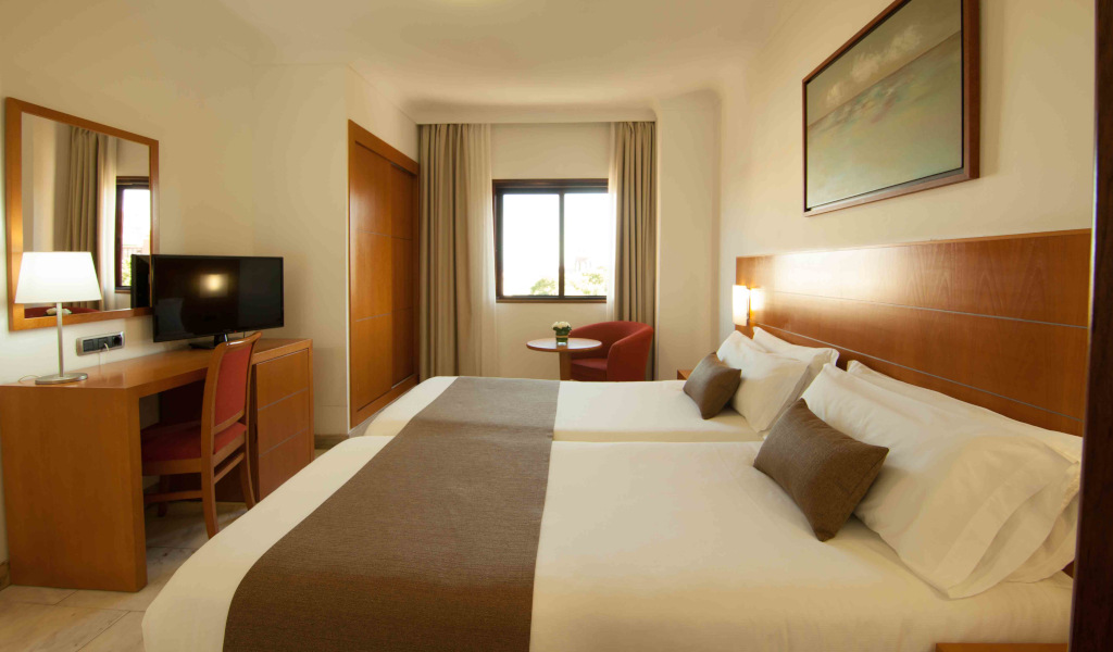 Chambre d'hôtel avec deux lits jumeaux à Tenerife, bureau et télévision.
