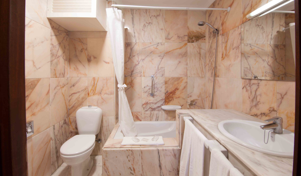 Salle de bain avec lavabo, toilette, baignoire et murs en marbre à Tenerife.