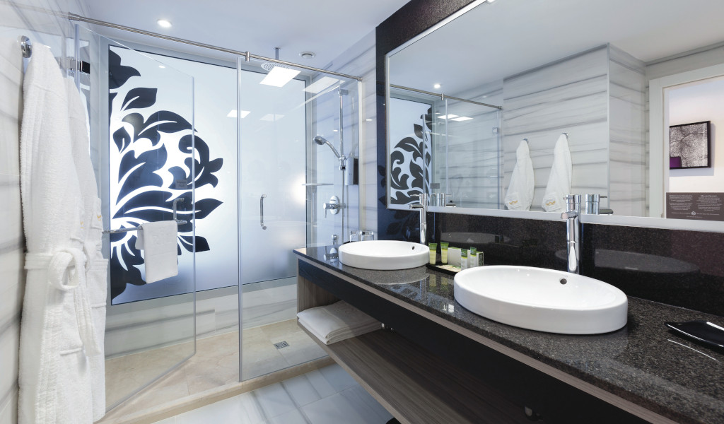 Salle de bain moderne à Tenerife avec deux lavabos et grande douche ornée de motifs noirs.