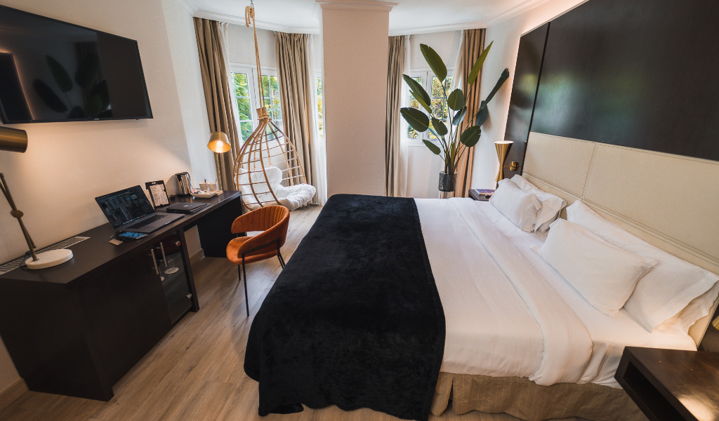 Chambre d'hôtel moderne à Tenerife avec lit double, bureau et fauteuil suspendu.