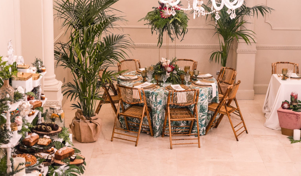 Table décorée pour un événement à Tenerife, avec chaises en bois et plantes vertes.