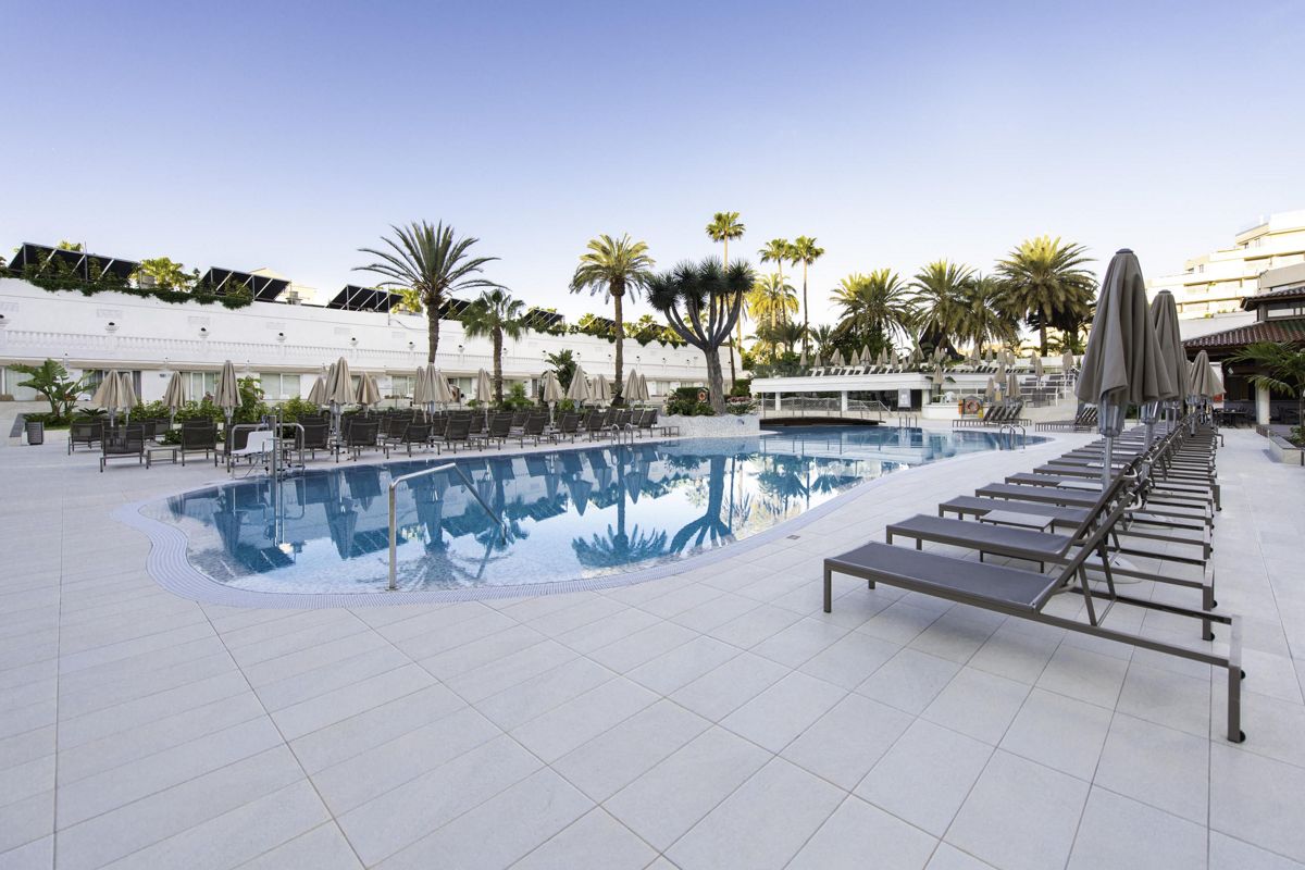 Piscine avec chaises longues et palmiers à Tenerife.