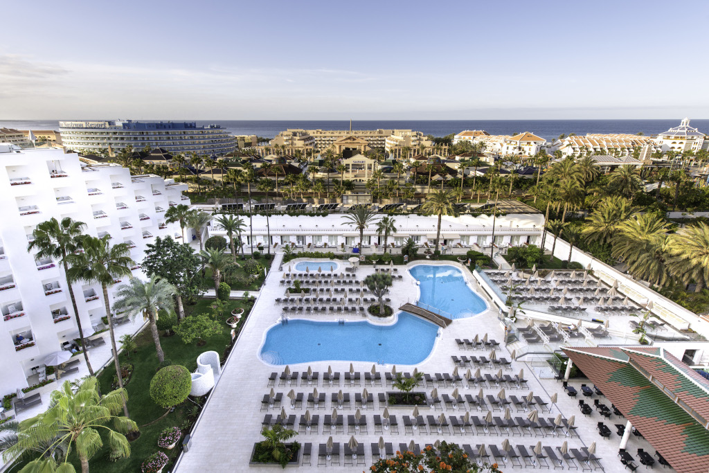 Piscine et transats à l'hôtel à Tenerife avec vue sur l'océan en arrière-plan.