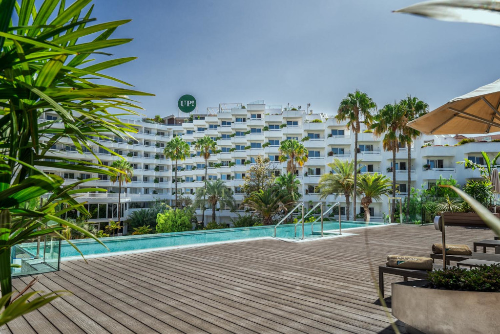 Piscine entourée de palmiers et bâtiment blanc à Tenerife.