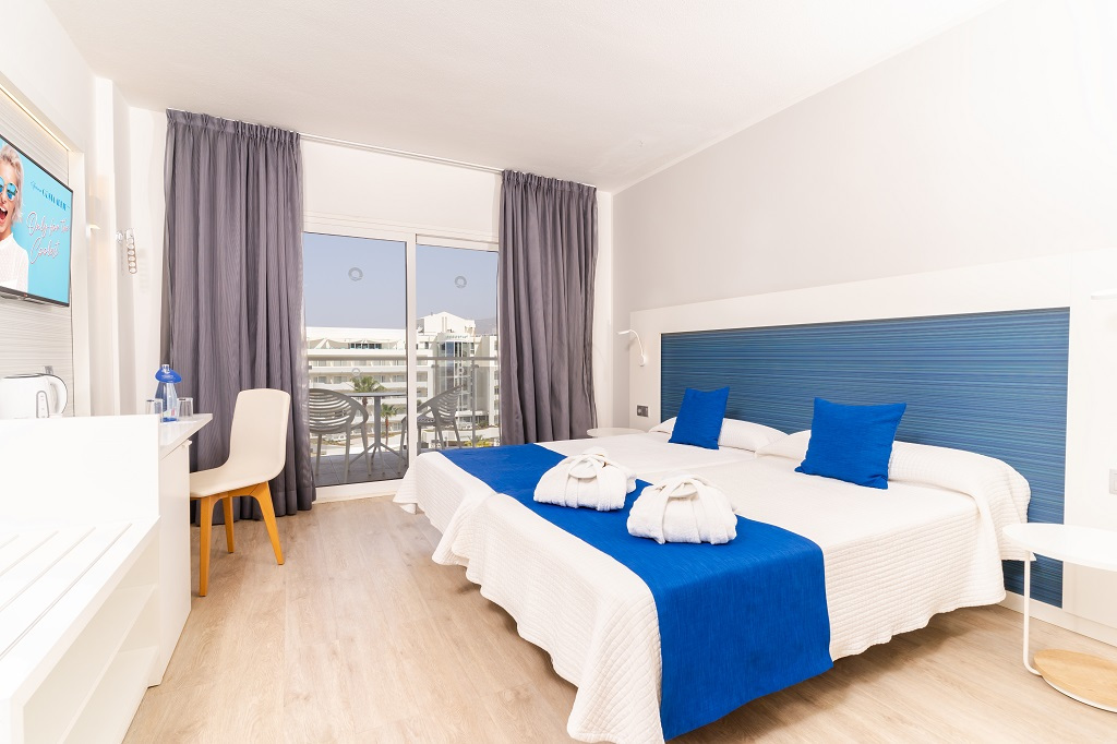 Chambre d'hôtel lumineuse avec lits jumeaux à Tenerife et vue sur le balcon.