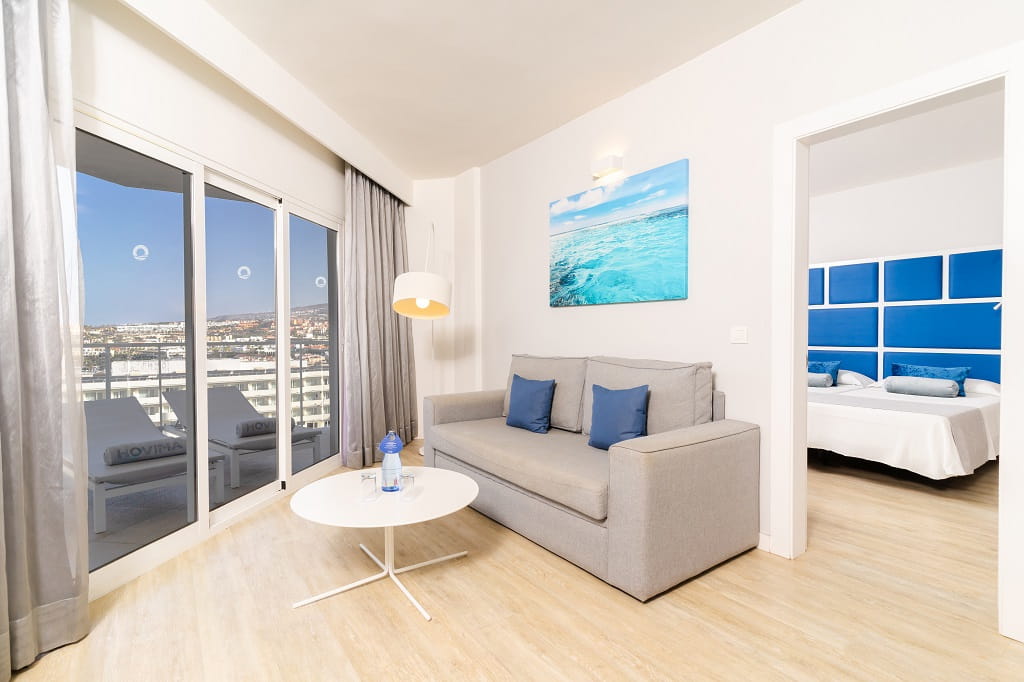 Salon moderne avec canapé gris, vue sur l'extérieur et chambre à coucher à Tenerife.
