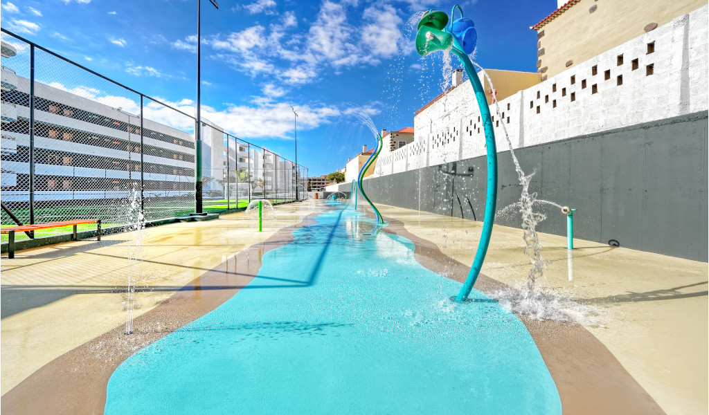 Aire de jeux aquatique à Los Cristianos, Tenerife, avec jets d'eau colorés.