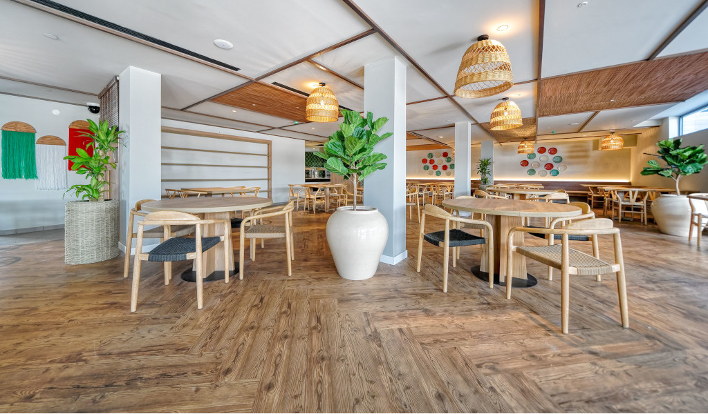 Intérieur d'un restaurant à Tenerife avec tables en bois et plantes vertes.