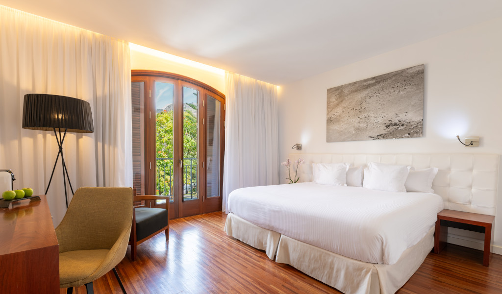 Chambre d'hôtel à Tenerife avec lit double et fenêtre donnant sur jardin.