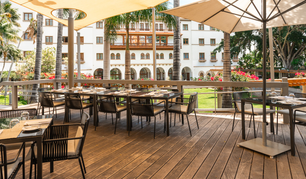 Terrasse de restaurant à Tenerife avec tables dressées et parasols.