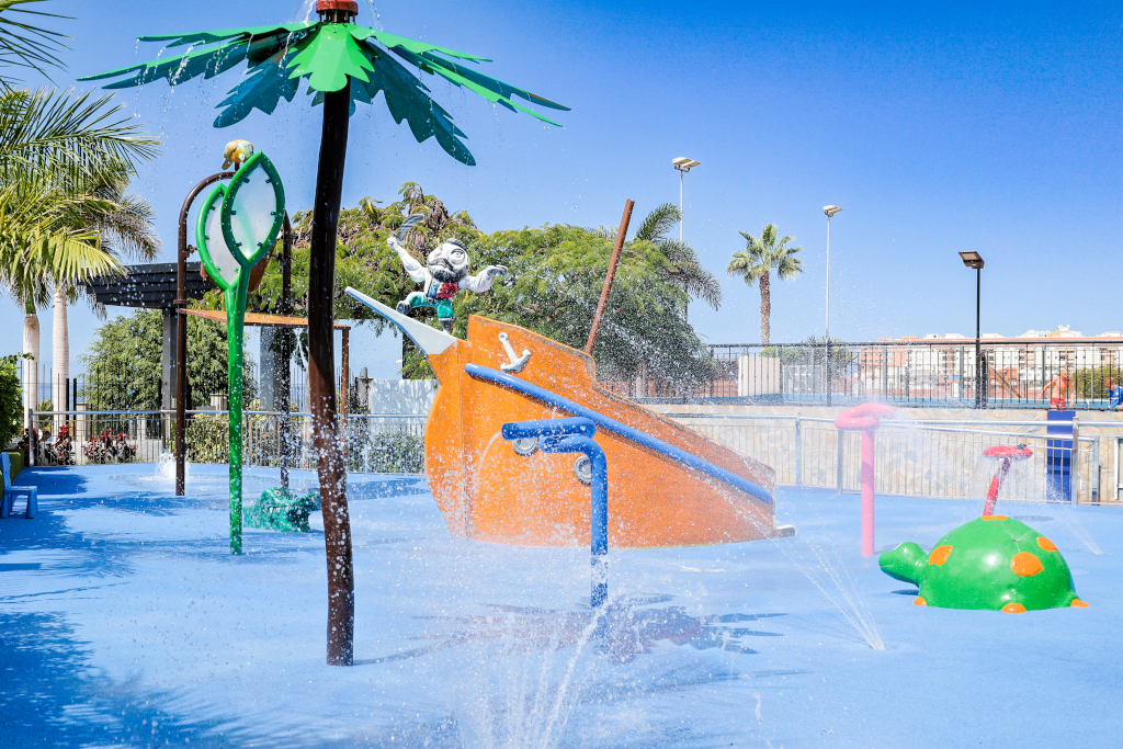 Aire de jeux aquatique à Tenerife avec palmier et structures colorées.