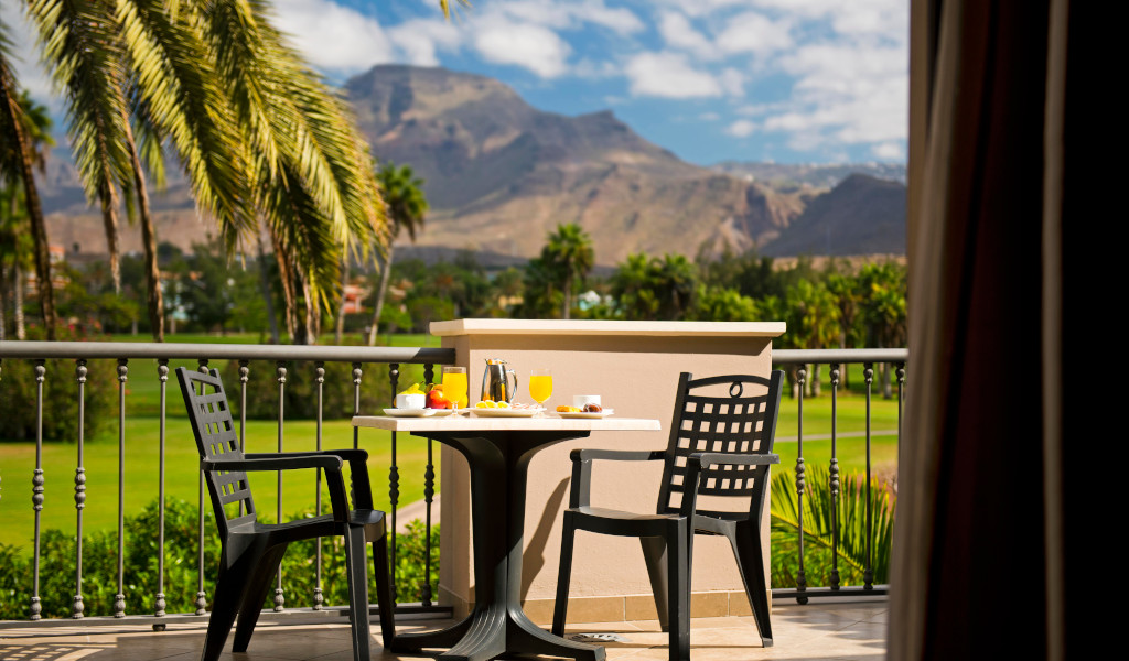 Deux chaises et table avec petit-déjeuner, palmiers et montagne à Tenerife.