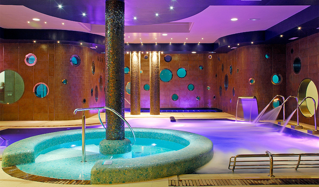 Jacuzzi illuminé dans un spa de Tenerife avec murs décoratifs circulaires.