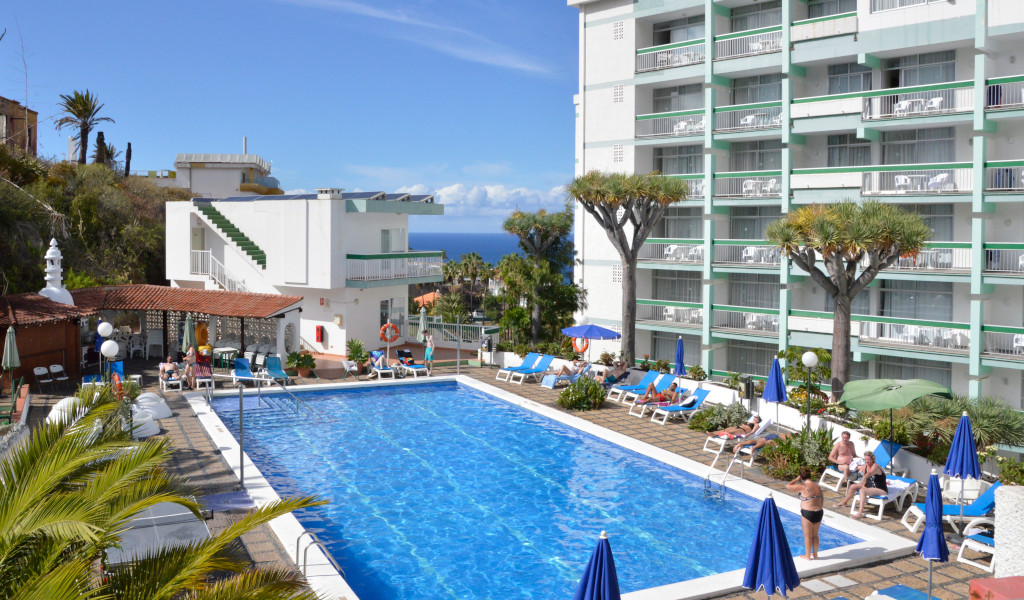 Piscine d'un hôtel à Tenerife avec vue sur l'océan et transats.