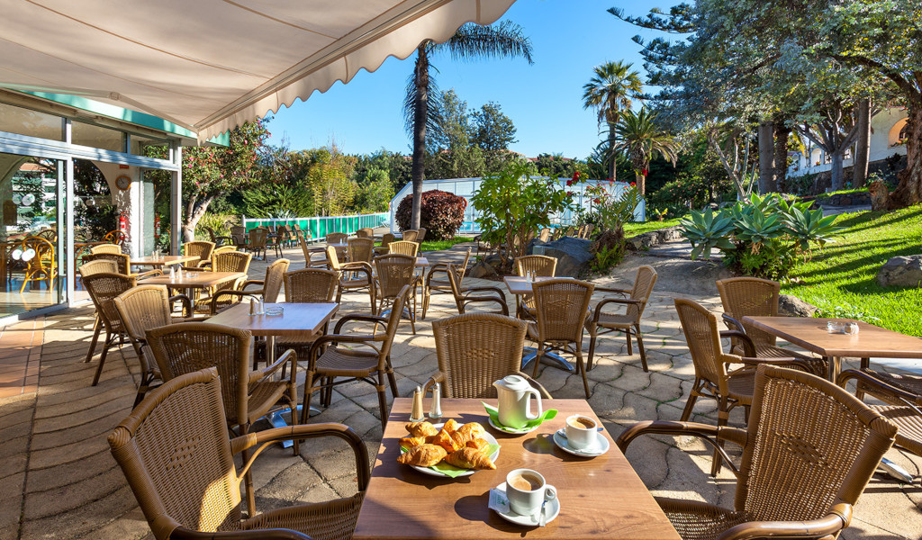 Terrasse de café avec chaises en osier et tables, croissants et café à Tenerife.
