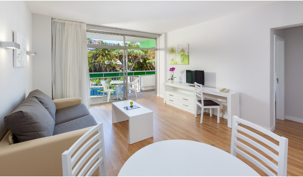 Salon moderne avec canapé, tables, balcon et vue sur les jardins à Tenerife.