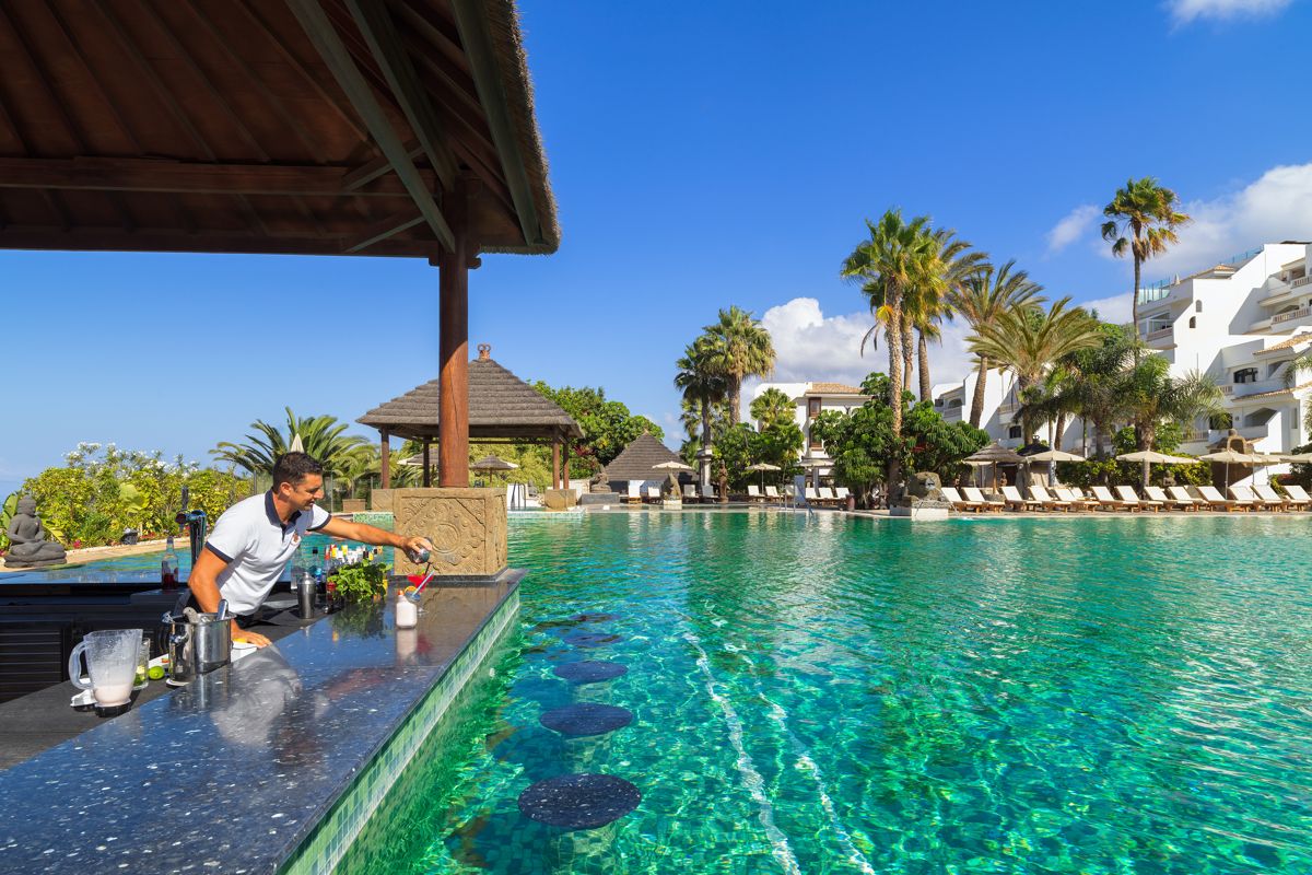 Serveur travaillant au bar de la piscine avec vue sur Costa Adeje, Tenerife.