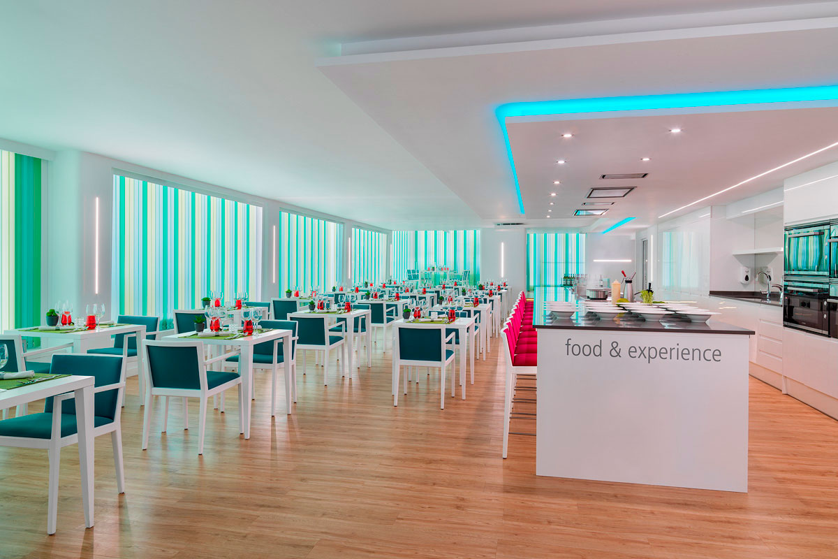 Salle de restaurant moderne à Tenerife avec tables disposées et lumière colorée. Texte: food & experience.