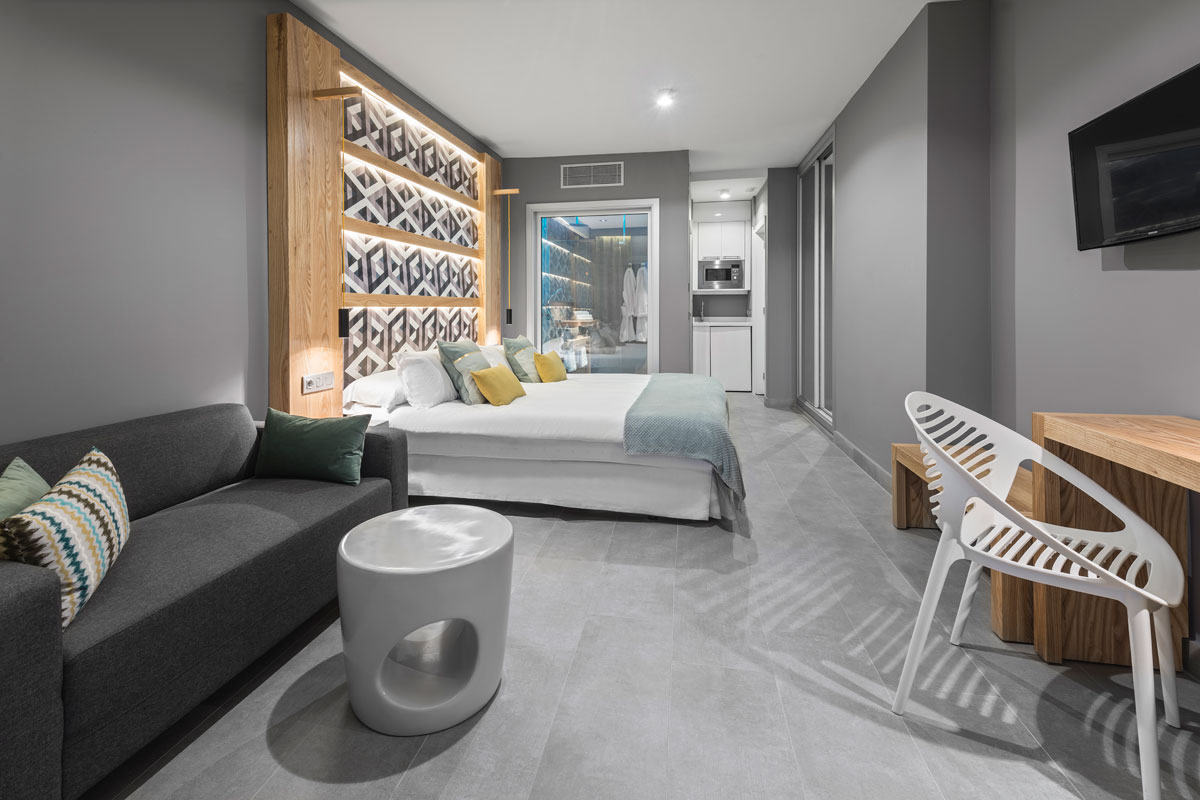 Chambre d'hôtel moderne à Tenerife avec lit, canapé et coin cuisine.