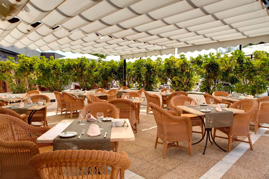 Terrasse ensoleillée avec tables entourées de chaises en rotin à Tenerife.