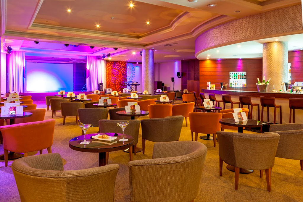 Salon avec tables, chaises et bar éclairé à Tenerife, scène en arrière-plan.