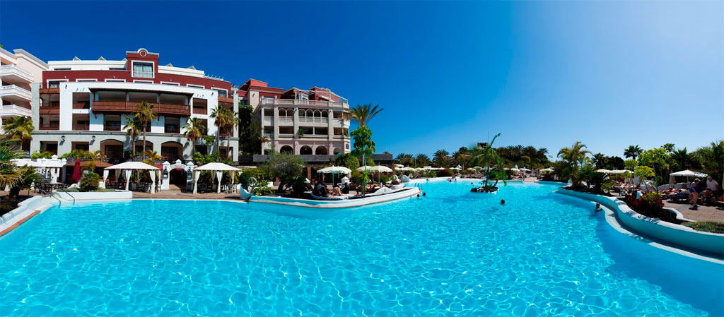 Piscine extérieure d'un hôtel à Tenerife avec ciel bleu et transats.