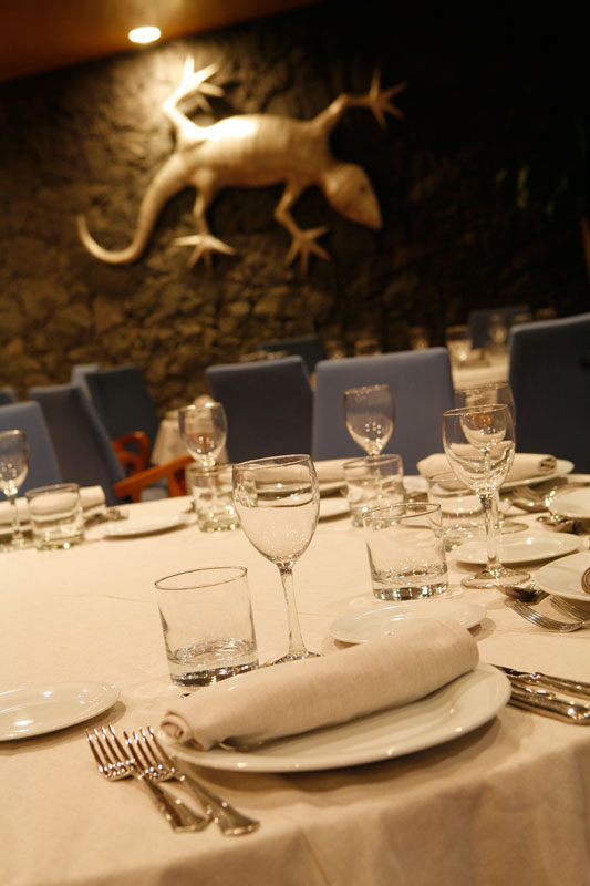 Table dressée avec couverts et verres, décoration murale de lézard à Tenerife.